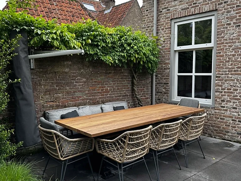 Wit kunststof kozijn met roeden in een bakstenen gevel, met terras